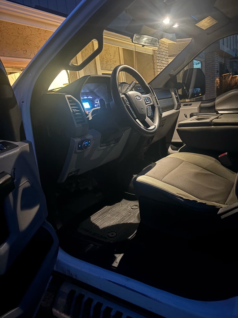 Interior of a blue Ford truck with dark dashboard, steering wheel, and tan and black seats visible in a garage setting