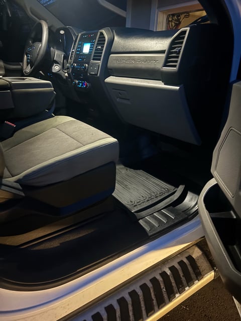 Interior of a pickup truck showing the steering wheel, dashboard, center console with controls, and gray upholstered front seats